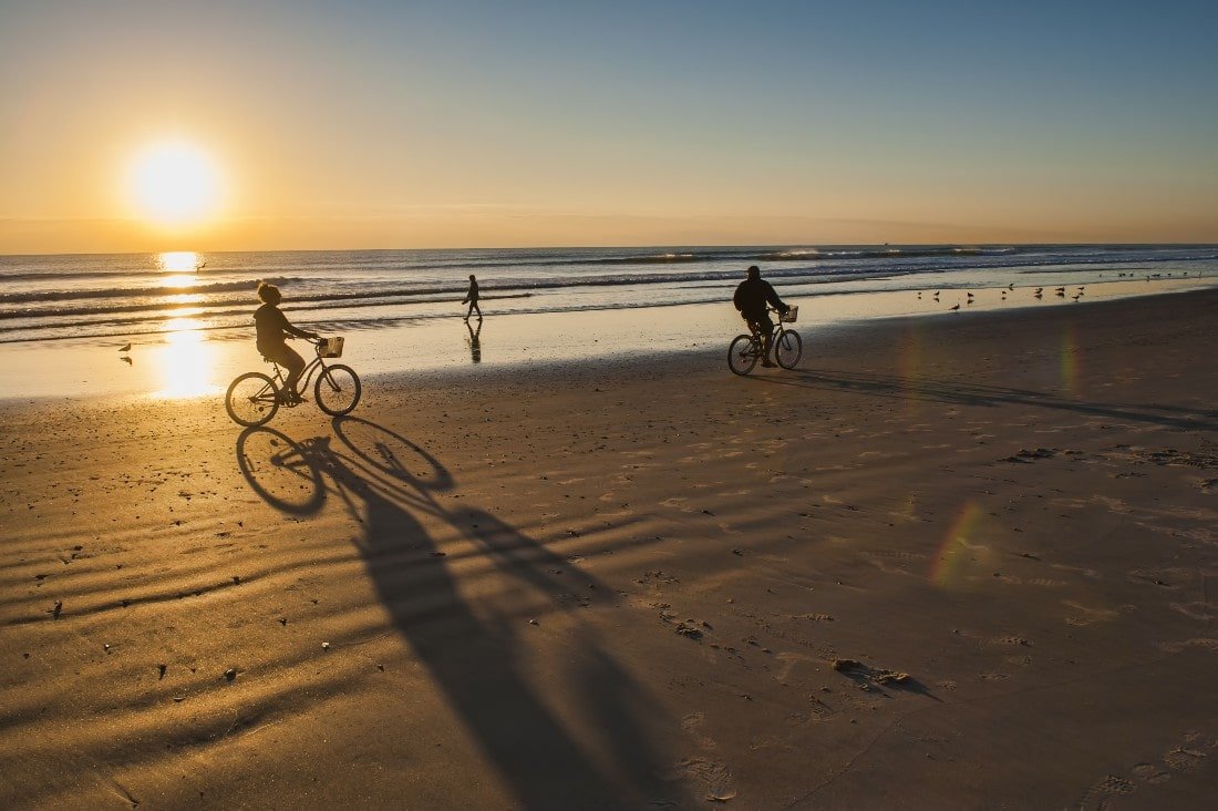 People cycling along the beach at sunset in Cocoa Beach Florida