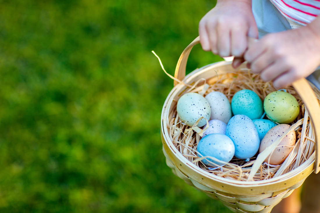 Child holding a basket of colored Easter eggs