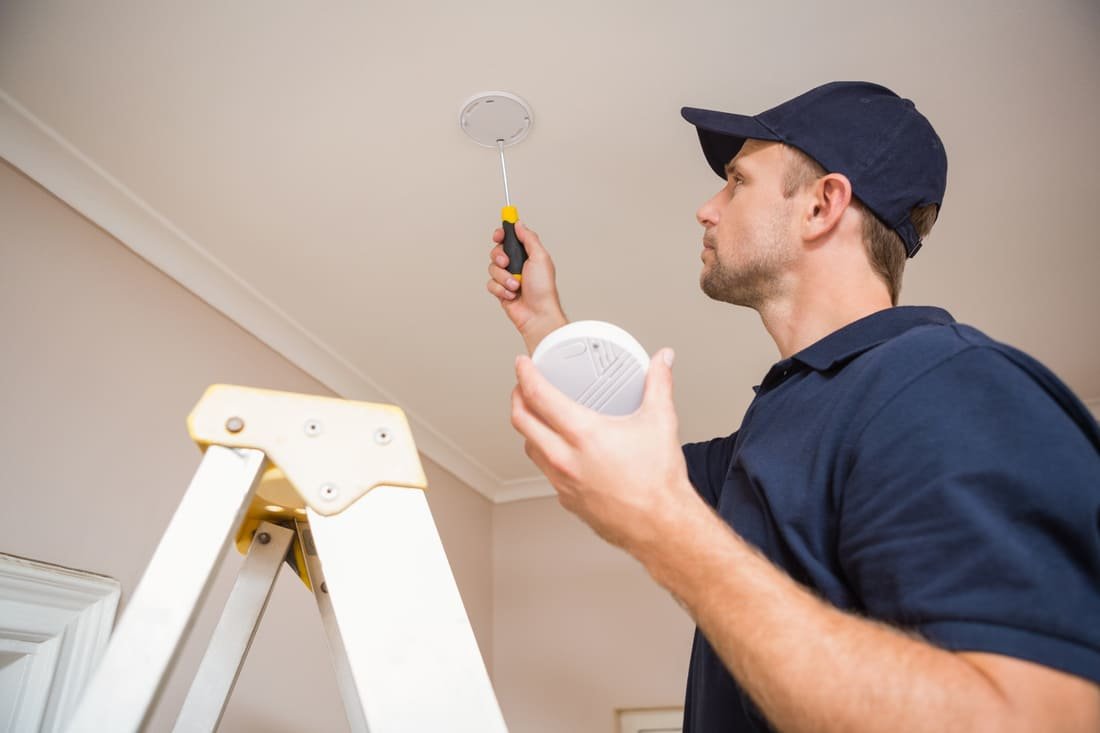 Man installing a smoke detector in a home