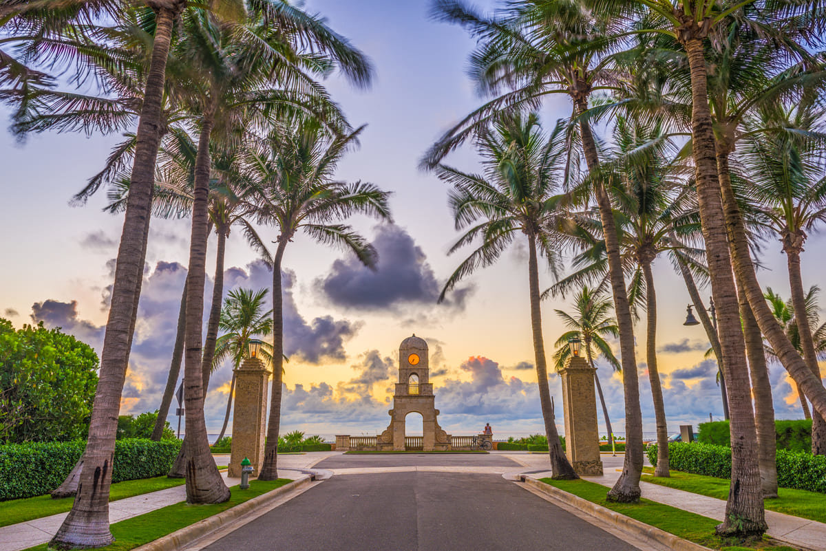 An arch way of palm trees leading to the water in West Palm Beach, Florida.