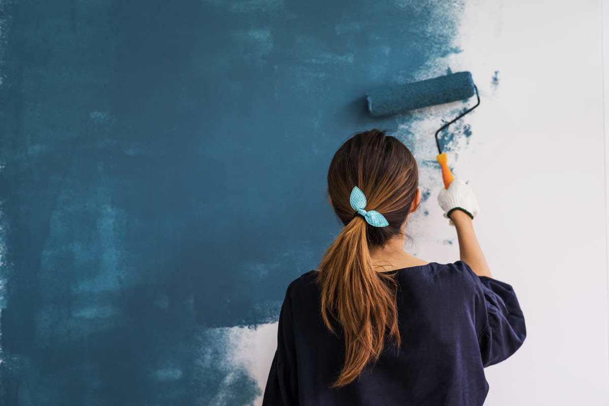A deep blue being painted on a wall of a home.