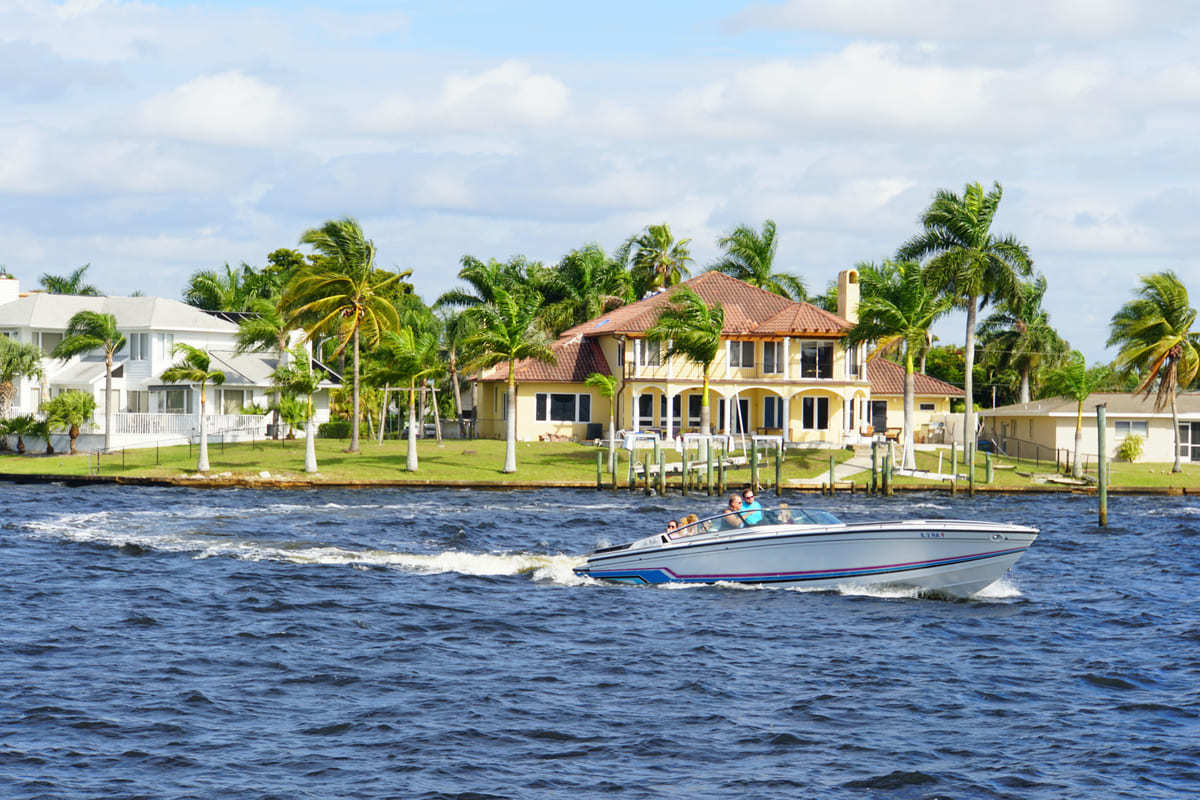 A stunning view of Cape Coral, FL on the water, with a luxurious home in the background.